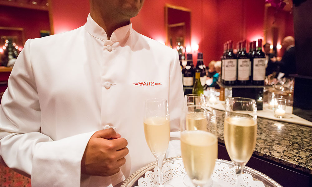 A Wattis Room waiter carries champagne