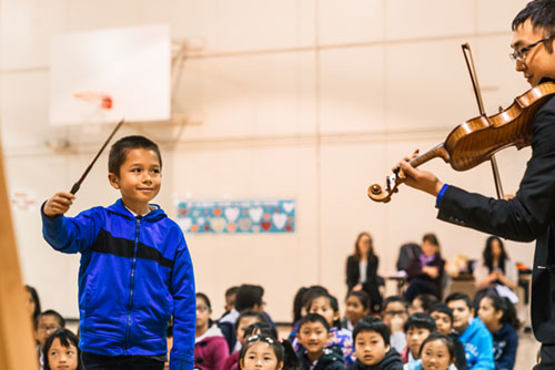 A child conducts a violinist during an AIM concert